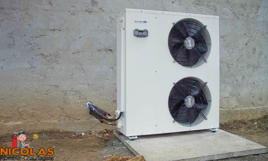 Unité extérieure d'un système de climatisation ou de pompe à chaleur, montée sur un mur extérieur, avec deux grands ventilateurs visibles.